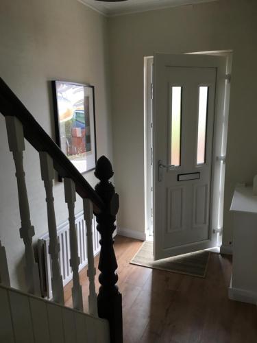 un pasillo con una puerta blanca y una escalera en Belfast Holiday Home en Belfast