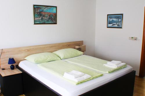 a bed with green sheets and towels on it at Bokun Apartments III in Sisak