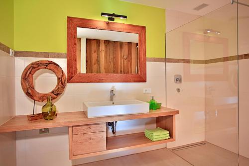La salle de bains est pourvue d'un lavabo, d'un miroir et d'une douche. dans l'établissement Familyparadies GAMPLALM, à Lana