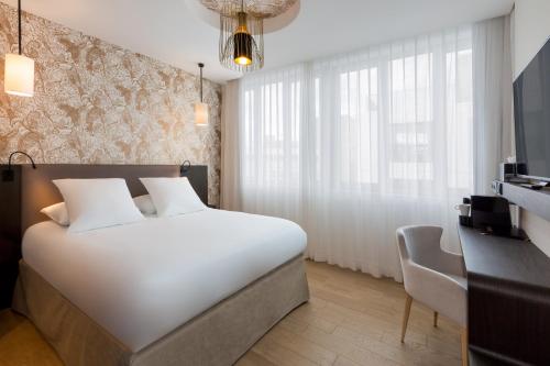 a bedroom with a large white bed and a desk at Hotel L'Arbre Voyageur - LILLE in Lille