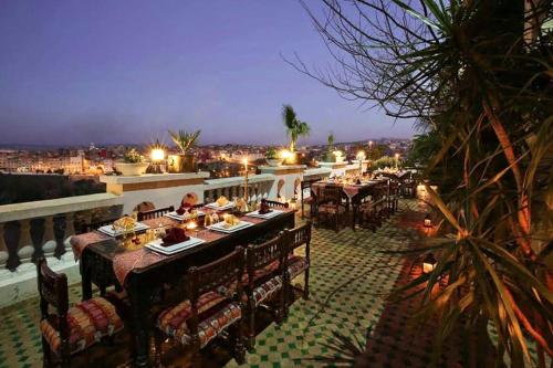 a restaurant with tables and chairs on a balcony at night at Riad Arabesque & Spa in Fès