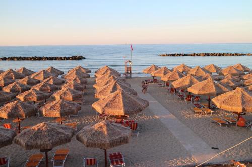 een stel rieten parasols en stoelen op een strand bij Holiday Dreams in Francavilla al Mare