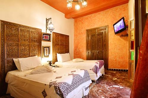 a hotel room with two beds and a tv at Riad Arabesque & Spa in Fès