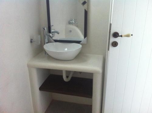 a bathroom with a white sink and a mirror at Plori Studios and Apartments in Aegiali