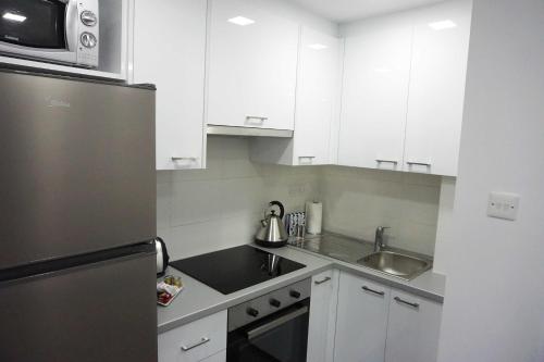 a kitchen with white cabinets and a stainless steel refrigerator at Lazuli Sea View Beachfront Ap 43 in Larnaka
