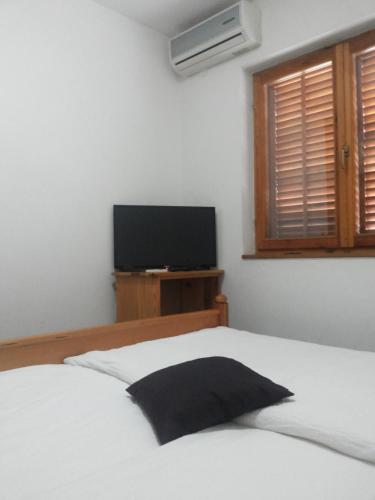 a bedroom with a white bed and a flat screen tv at Motel Jelčić in Čapljina