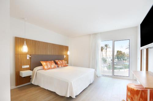 a bedroom with a white bed and a large window at Iberostar Playa de Muro in Playa de Muro