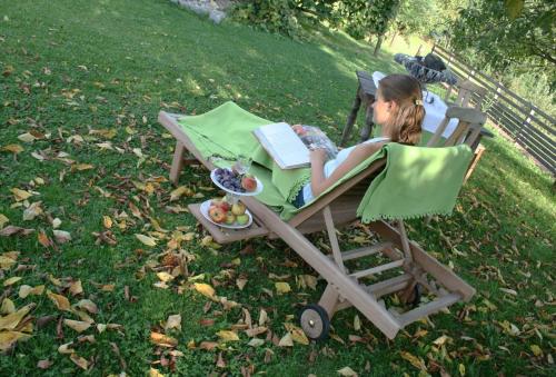 a woman sitting in a lawn chair with a book at Sonnenhaus Grandl in Feldbach
