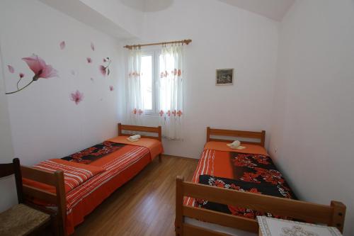 two beds in a room with white walls and a window at Marašić in Ždrelac