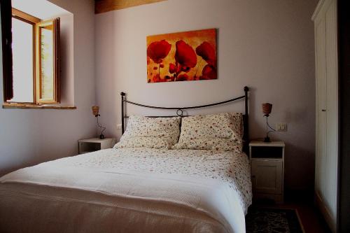 a bedroom with a bed with white sheets and red flowers at Al Castello in San Severino Marche