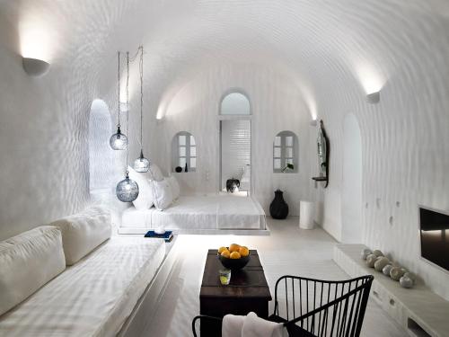 a white room with a bed and a table at 1864 The Sea Captain's House in Oia