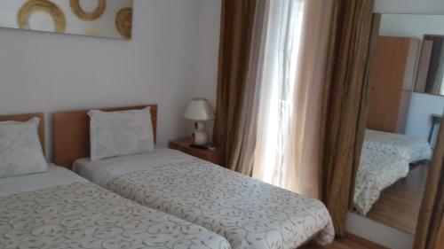 a small bedroom with two beds and a mirror at Alojamento Cesarini in Montijo