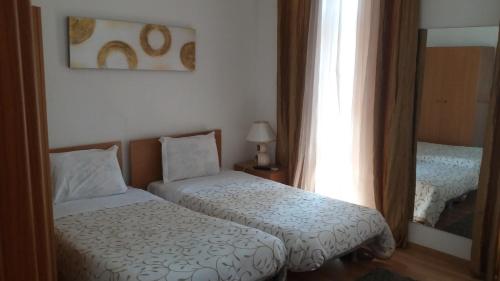a small bedroom with two beds and a mirror at Alojamento Cesarini in Montijo
