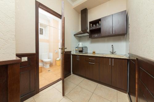 a kitchen with wooden cabinets and a bathroom with a toilet at Sadko on Shevchenko in Anapa