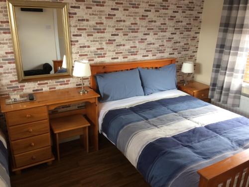 1 dormitorio con cama, tocador y espejo en Amore Bed & Breakfast, en Derry Londonderry