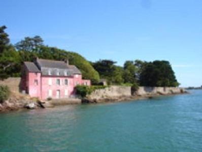 a pink house on the shore of a body of water at Chambres d'Hôtes Ty Mezad in Séné