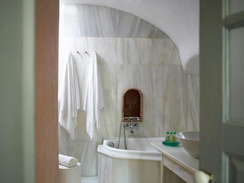 a white bathroom with a tub and a sink at 1864 The Sea Captain's House in Oia