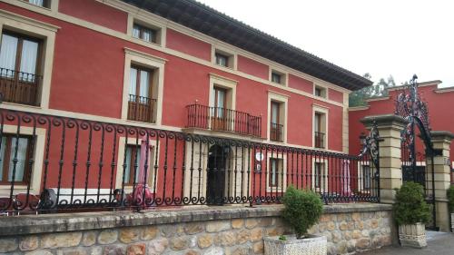 un edificio rojo con una valla delante en Posada Santa Eulalia, en Villanueva de la Peña