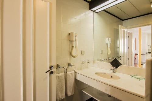 un bagno bianco con lavandino e specchio di Apartamentos Turisticos Avenue Park a Funchal