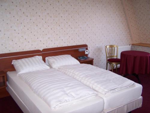 Schlafzimmer mit einem Bett mit weißer Bettwäsche und einem Tisch in der Unterkunft De Herberg van Loon in Loon