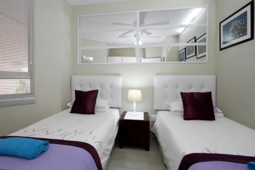 Un dormitorio con dos camas y un ventilador de techo. en 6 Ipanema Beach, en Durban