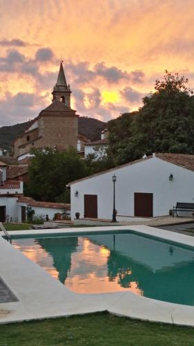 a pool in front of a building with a sunset at Casona Del Duende in Alájar