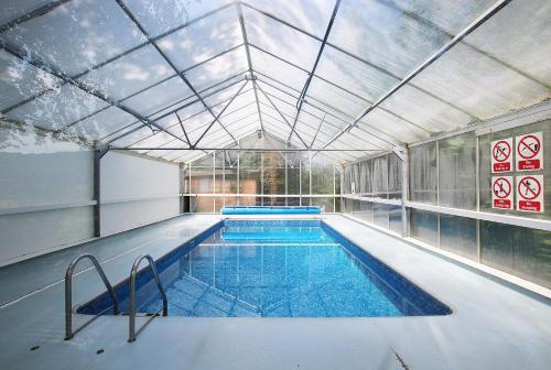 a large indoor swimming pool with a glass ceiling at Pheasant Walk at Eaton Manor in Church Stretton