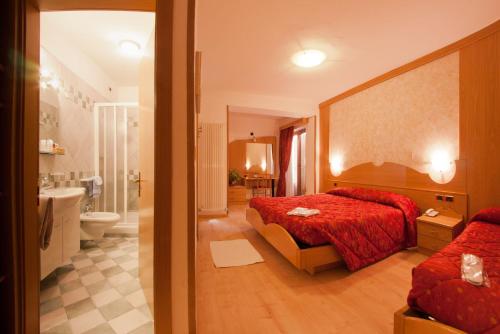 a bedroom with a red bed and a bathroom at Hotel Cristallo in Andalo