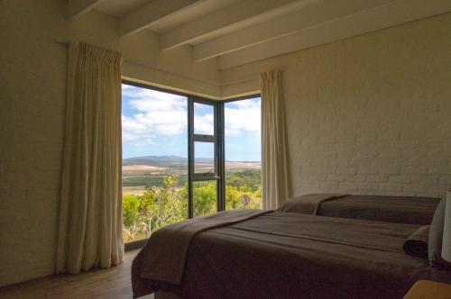 - une chambre avec un lit et une grande fenêtre dans l'établissement Phillipskop Mountain Reserve, à Stanford