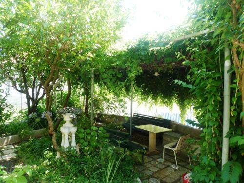 a garden with a bench and a table under a pergola at Rooms Ljubo in Dubrovnik