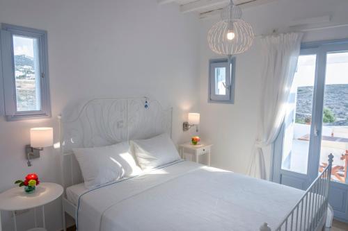 a white bedroom with a bed and a window at Passos Villas in Parasporos