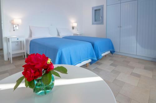 a room with two beds and a vase with red flowers on a table at Passos Villas in Parasporos