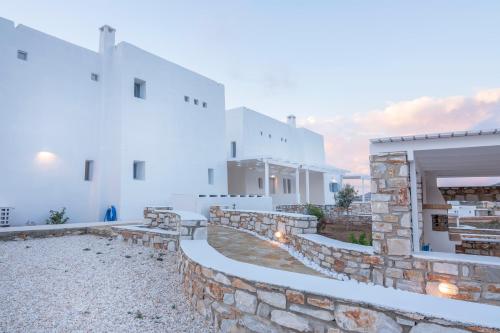 a row of white buildings with a stone wall at Passos Villas in Parasporos