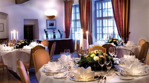 a dining room with white tables and chairs with flowers at Radisson Blu Hotel Altstadt in Salzburg