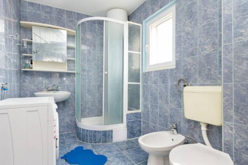 uma casa de banho em azulejos azuis com um WC e um lavatório em Apartmani Dotur em Split