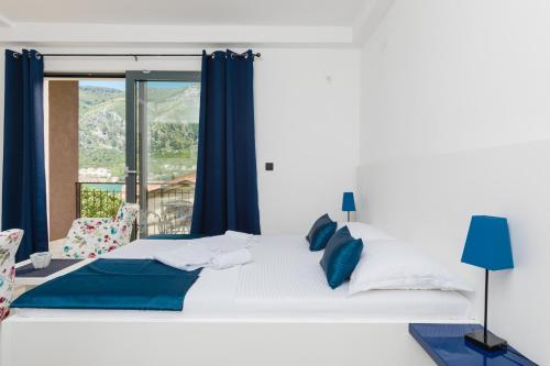 a white bed with blue pillows and a window at Apartments 26 in Kotor