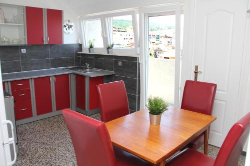 cocina con mesa de madera y sillas rojas en Martin Apartment, en Šibenik