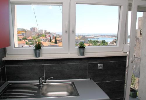 eine Küche mit einem Waschbecken und zwei Fenstern in der Unterkunft Martin Apartment in Šibenik