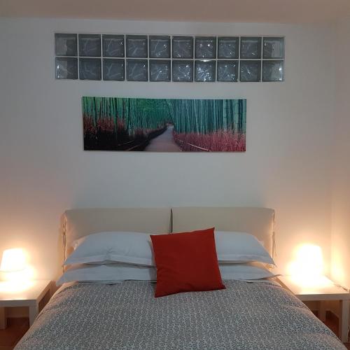 a bedroom with a bed with a painting on the wall at L'albero Del Pepe in Fiano Romano