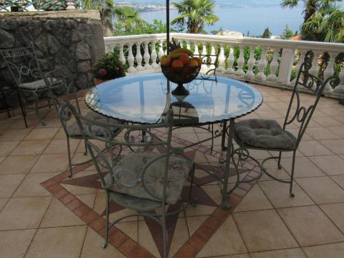 una mesa de cristal con sillas y un bol de fruta. en Apartments Villa Palme, en Opatija
