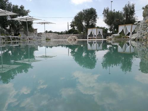a pool of water with tables and umbrellas at Willaria Country House in Cursi