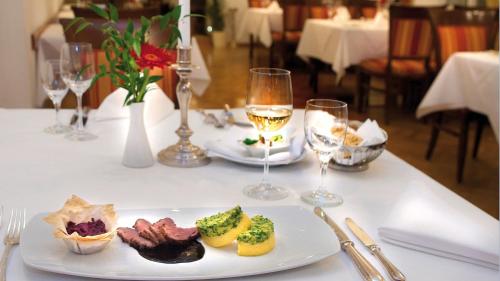 a table with a plate of food and glasses of wine at Radisson Blu Hotel Altstadt in Salzburg