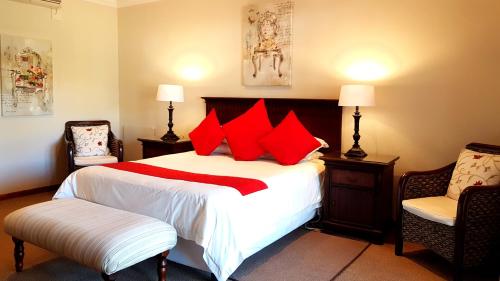 a bedroom with a bed with red pillows and two chairs at The Hut in Burgersdorp