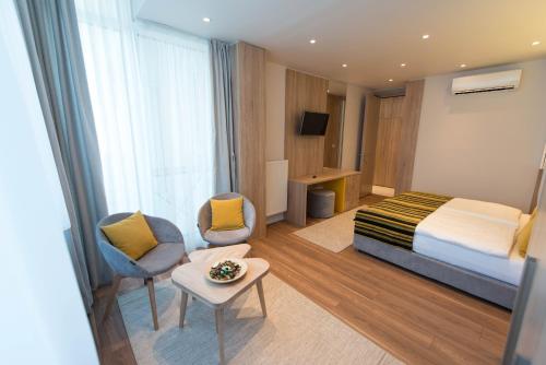 um quarto de hotel com uma cama e duas cadeiras e uma mesa em Sarajevo Daily Apartments em Sarajevo