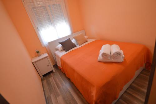 a bedroom with an orange bed with towels on it at Apartamento Playa Capellans - Salou in Salou