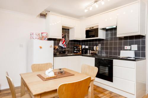 a kitchen with white cabinets and a wooden table and chairs at Henley-on-Thames Studio Apartment in Henley on Thames