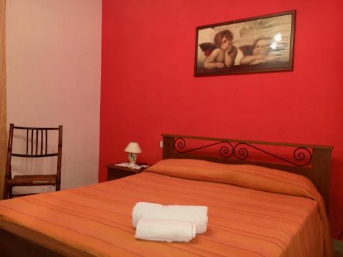 a red bedroom with a bed with two towels on it at Appartamento al mare Cusumano in Trappeto