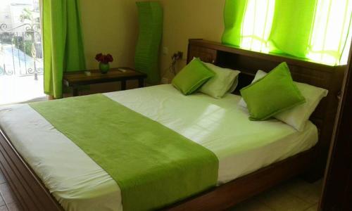 a bedroom with a large bed with green sheets and pillows at Residence Mont Choisy in Mont Choisy