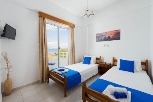 two beds in a room with a window at Annabel Apartments in Theologos