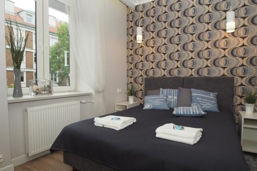 a bedroom with a bed with towels on it at Grand-Tourist Center Point Apartments in Gdańsk